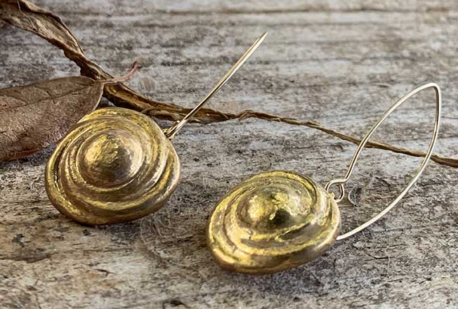 עגילים יחודיים עבודת יד מסותתים מחימר עם שכבת גלזורה ועיטורי זהב 24 קארט על גבי מתלה העשוי גולדפילד.